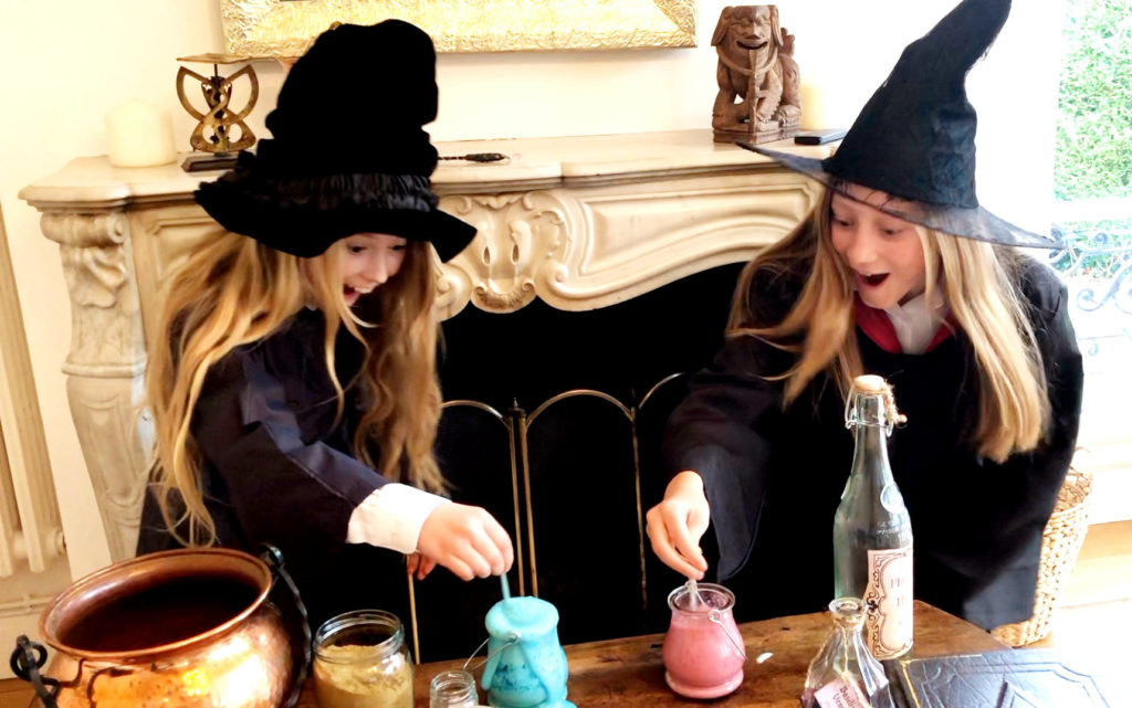 Two happy girls wearing witch's clothes brewing a potion