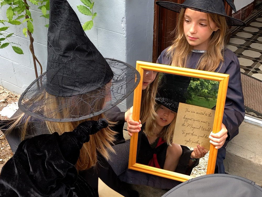 A girl dressed as a witch plays treasure hunt reading in the mirror the clue that is reversed